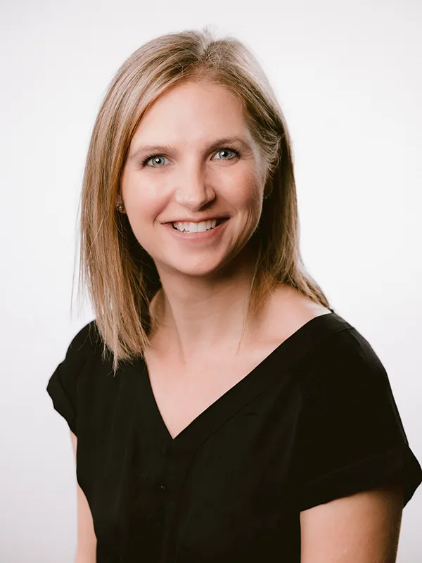A smiling woman with blonde hair wearing a black blouse