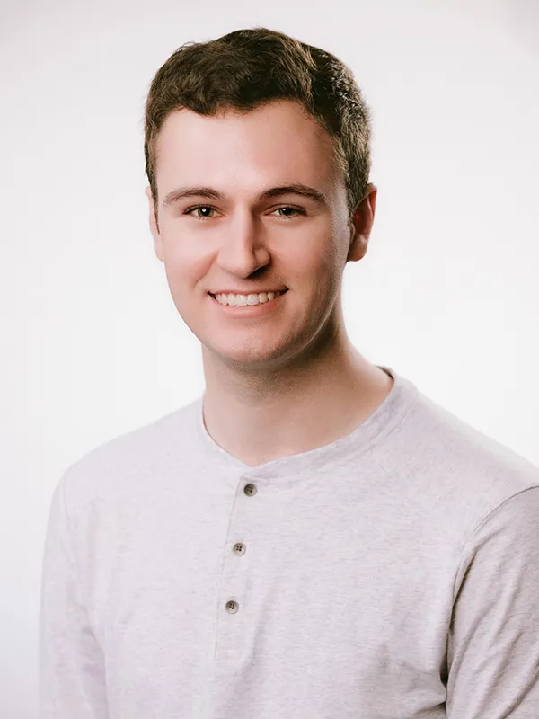 A smiling man wering a light gray tee-shirt