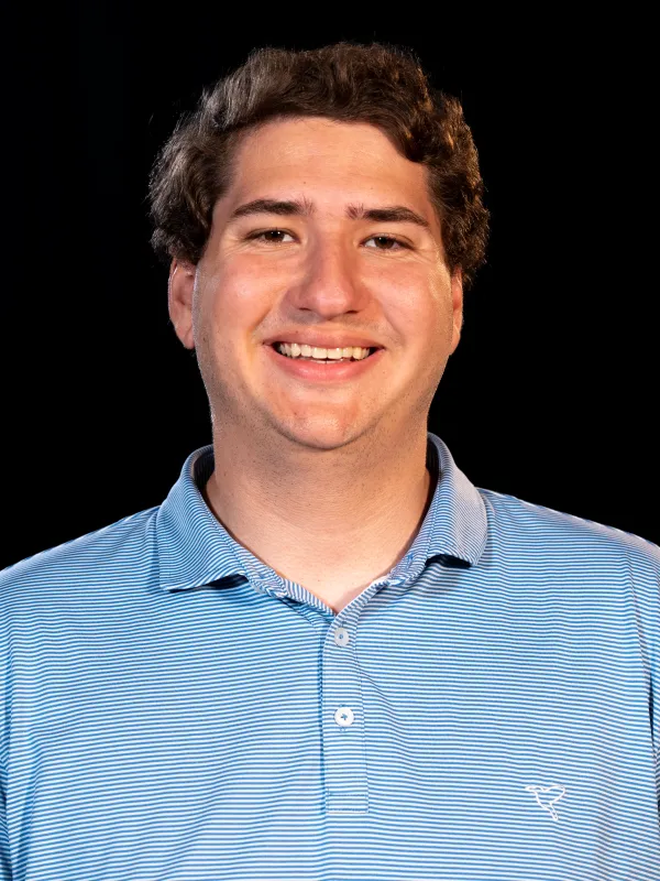 Evan smiling with brown hair wearing a blue polo shirt