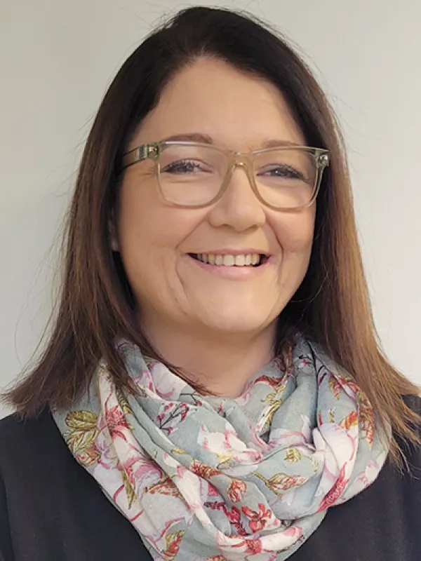 A smiling woman wearing a scarf and eyeglasses