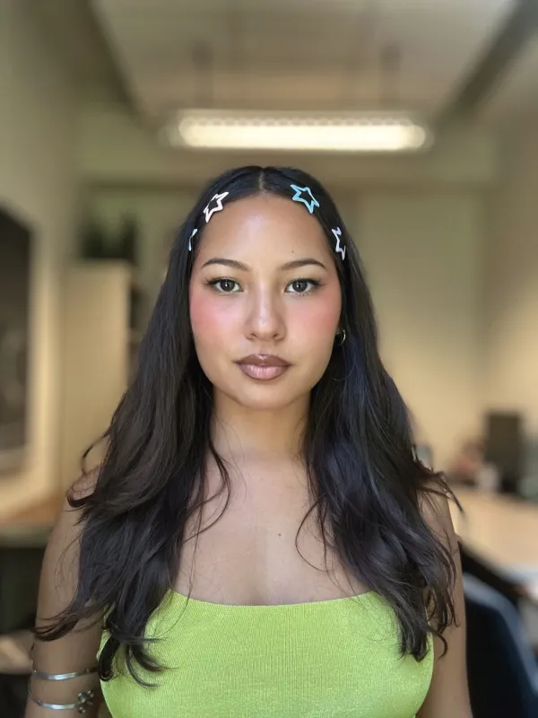 Karina wearing a green shirt and has her hair down with 4 bobby pins that are star shaped.